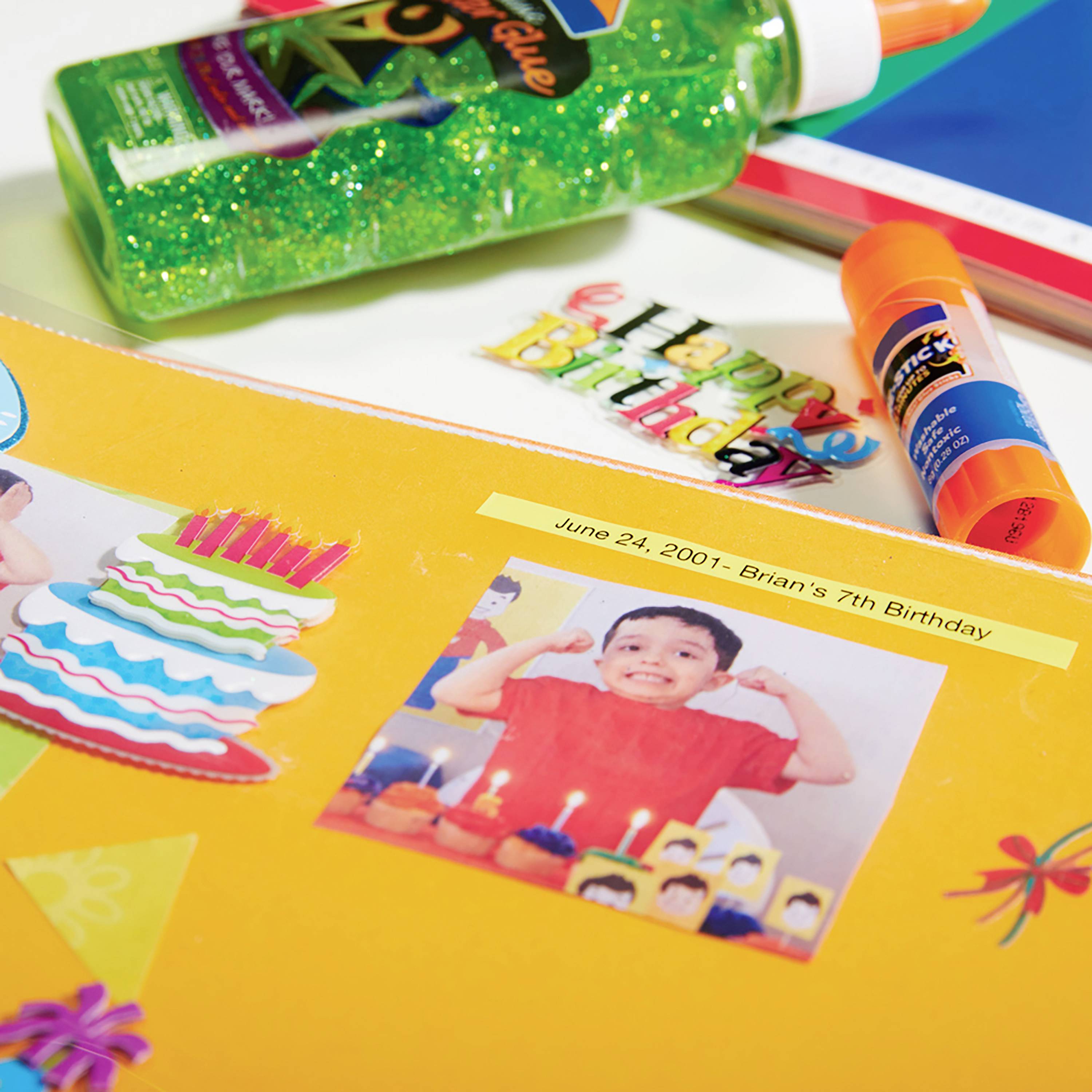 An orange craft project with a photo of a child showing cake. Text at the top: '24th June 2001 - Brian's 7th Birthday'.