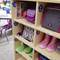 'A shelf in a classroom with lockers. School items such as books, lunchbox, rucksack, sunglasses, wellies and toys are stored in various compartments.'