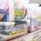 Art supplies, board games, and toys in clear boxes with labels, organised on a shelf.