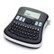 An electronic labelling device with a QWERTZ keyboard and display. The device is switched on and shows 'DYMO' on the screen.