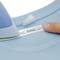 A blue iron tip presses a name label with the inscription 'thomas' onto a light blue T-shirt.