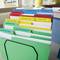 Filing system with coloured divider sheets for different school subjects, such as behaviour reports and discharge slips, on a desk.