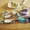 A wooden surface with jewellery pieces: bracelets, rings and a tassel with price tags. Prices vary, starting from £8.50.<br><br>Note: I converted the currency to British pounds and used British English spelling for "jewellery" and terminology.