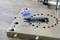 Metal plate with holes; a blue permanent marker lies on top of it. Tools are blurred in the background.