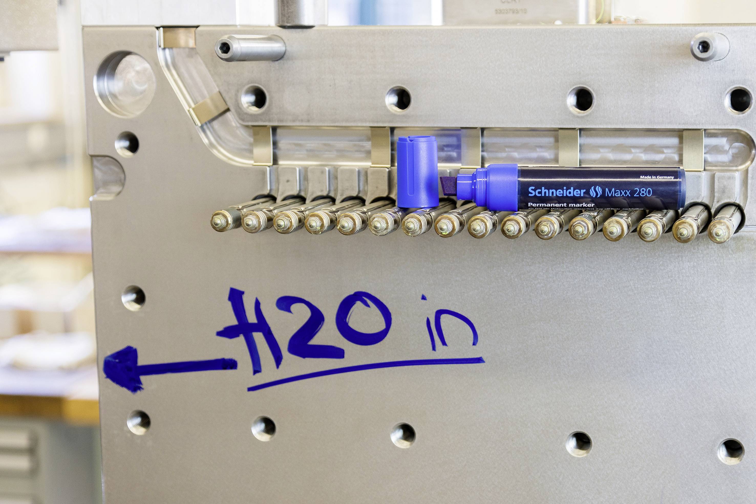 A metal surface with a blue marker drawing an arrow and 'H2O in'. A blue pen lies beside it.