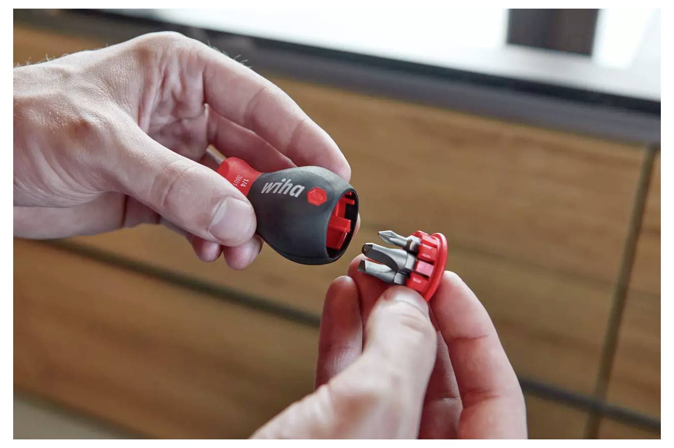 A person is holding a small, interchangeable screwdriver set, showcasing the detachable handle and multiple bits for versatile use.