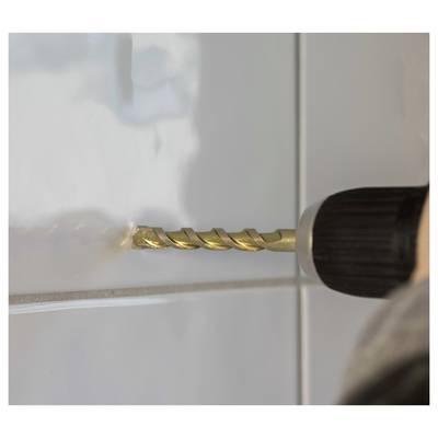 Close-up of a power drill with a gold bit drilling into a tiled wall, creating dust at the hole.<br>