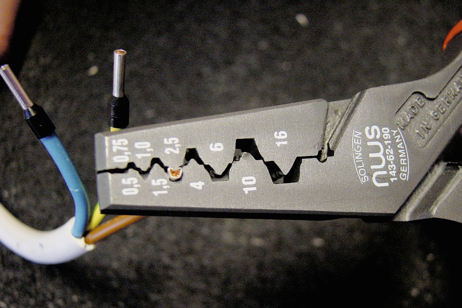 Wire cutters slice coloured cables. The tool shows size specifications in millimetres, ranging from 0.5 to 16. Wire ends are of varying lengths.