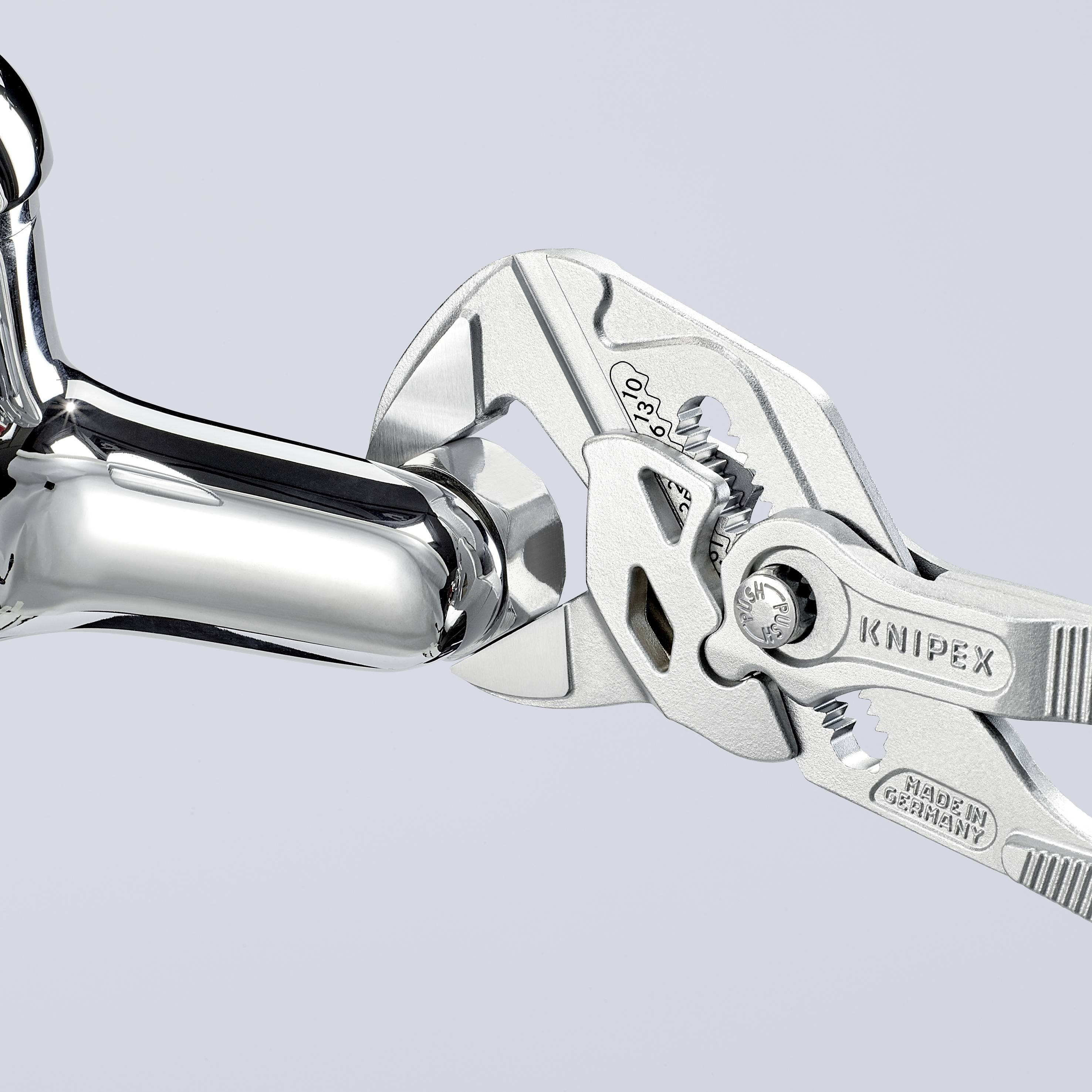 A chrome-plated adjustable spanner holds a gleaming, chrome-plated pipe, demonstrating precision and robustness when working with plumbing installations.