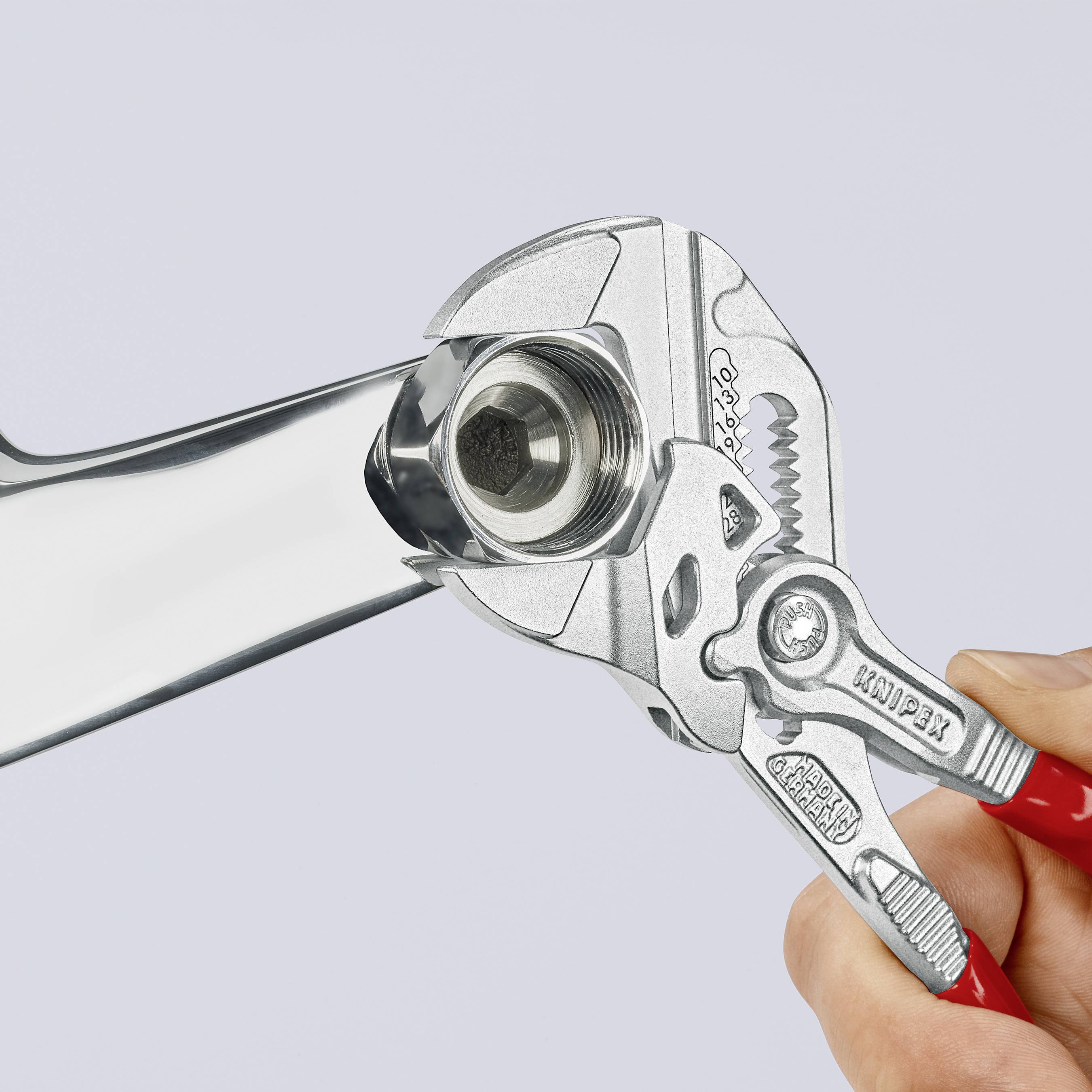 A hand holds an adjustable spanner gripping a nut on a wrench. The focus is on the handling of the tools.