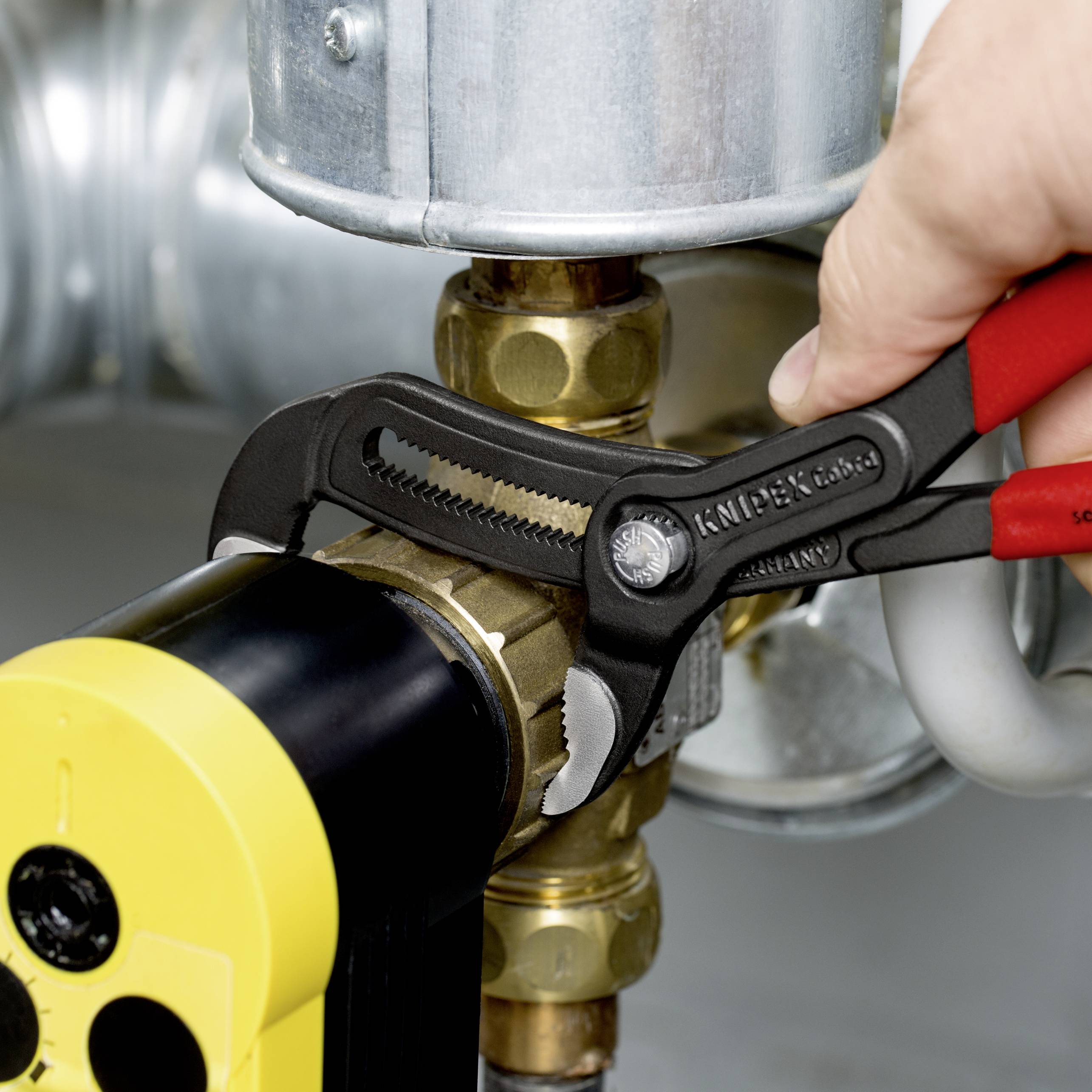 'Hand using an adjustable wrench to tighten a screw connection on a metal pipe.'