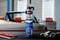 A can of 'Caramba Express Reifendicht', a tire sealant, on a table with wrenches and pliers, blurred classic car in the background.