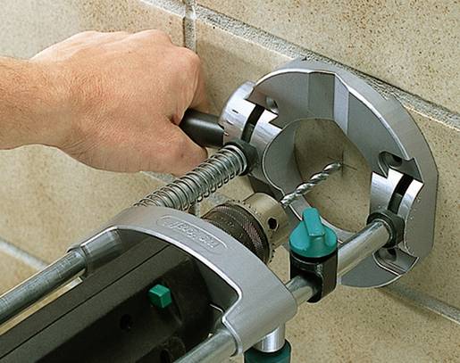 A hand operates a drill with a tile drilling system on a tiled wall. The system securely holds the drill bit in place.