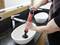 A person is using a plunger in a sink in the bathroom to clear a blockage.