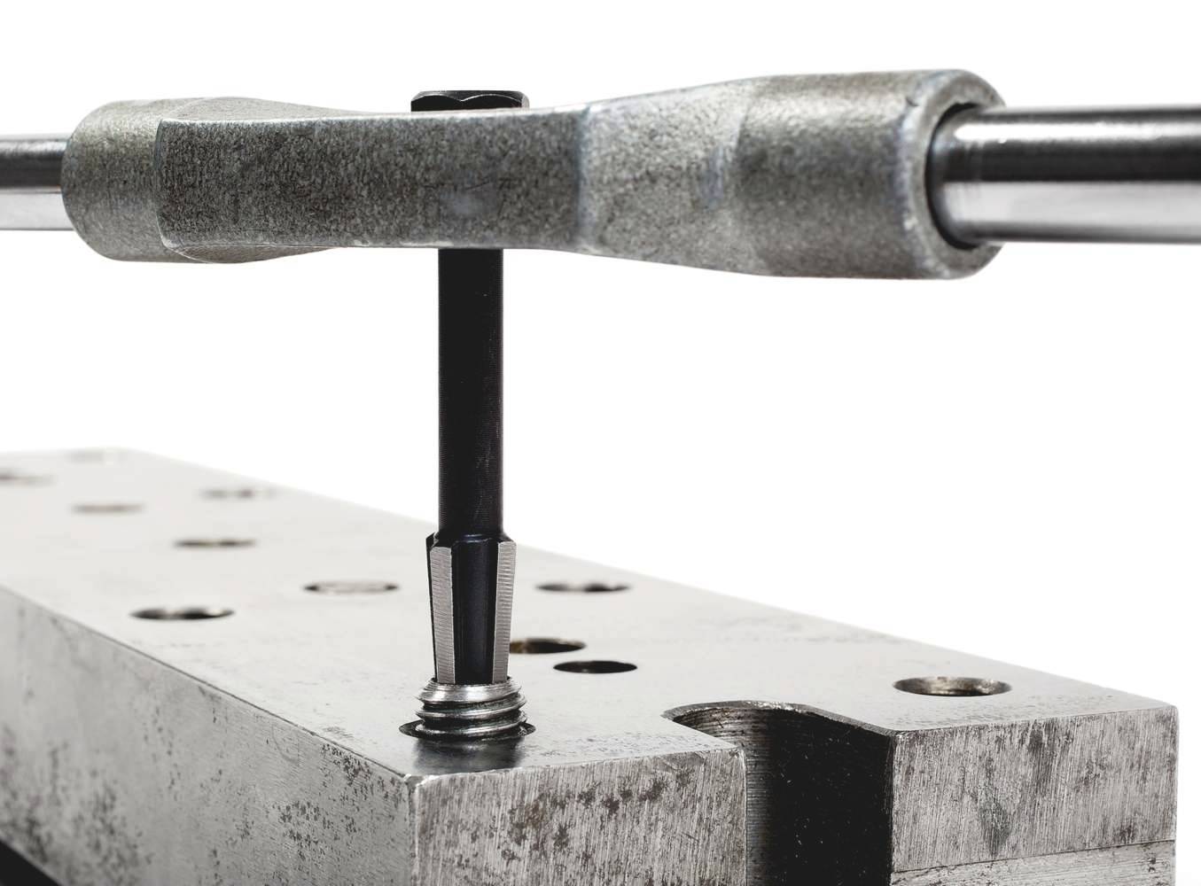 A metal thread cutter is used to cut a thread into a hole in a metal block.