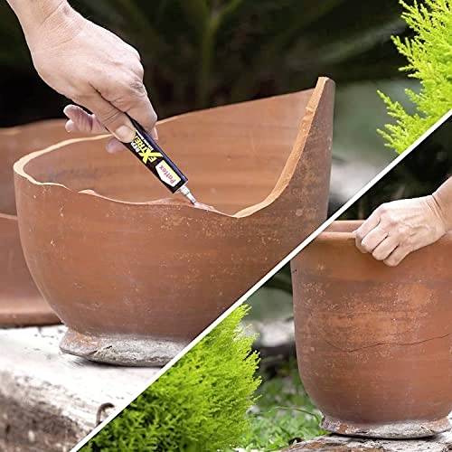 A person uses adhesive to repair a broken terracotta pot outdoors, aligning pieces together carefully. Another intact pot is in the background.
