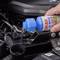 A hand pours blue liquid from a SONAX Xtreme bottle into the container of a car product. Engine in the background.