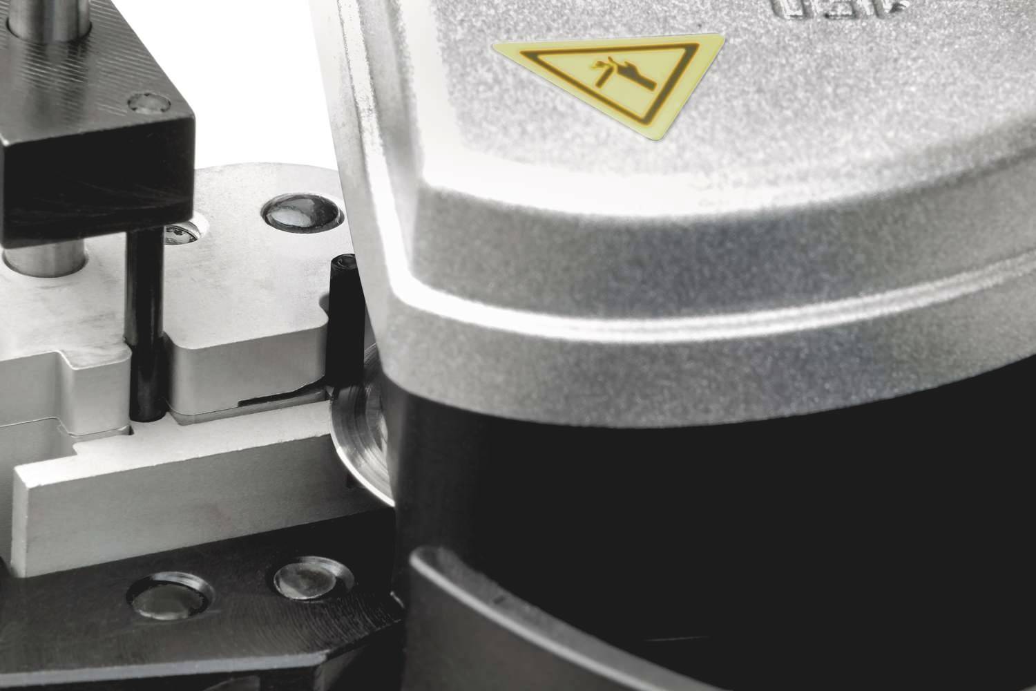Machine component in close-up with yellow warning symbol indicating a hazard.