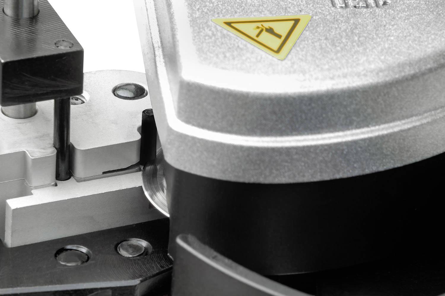 A machine is bending a piece of metal. A yellow warning symbol indicates the need for caution.