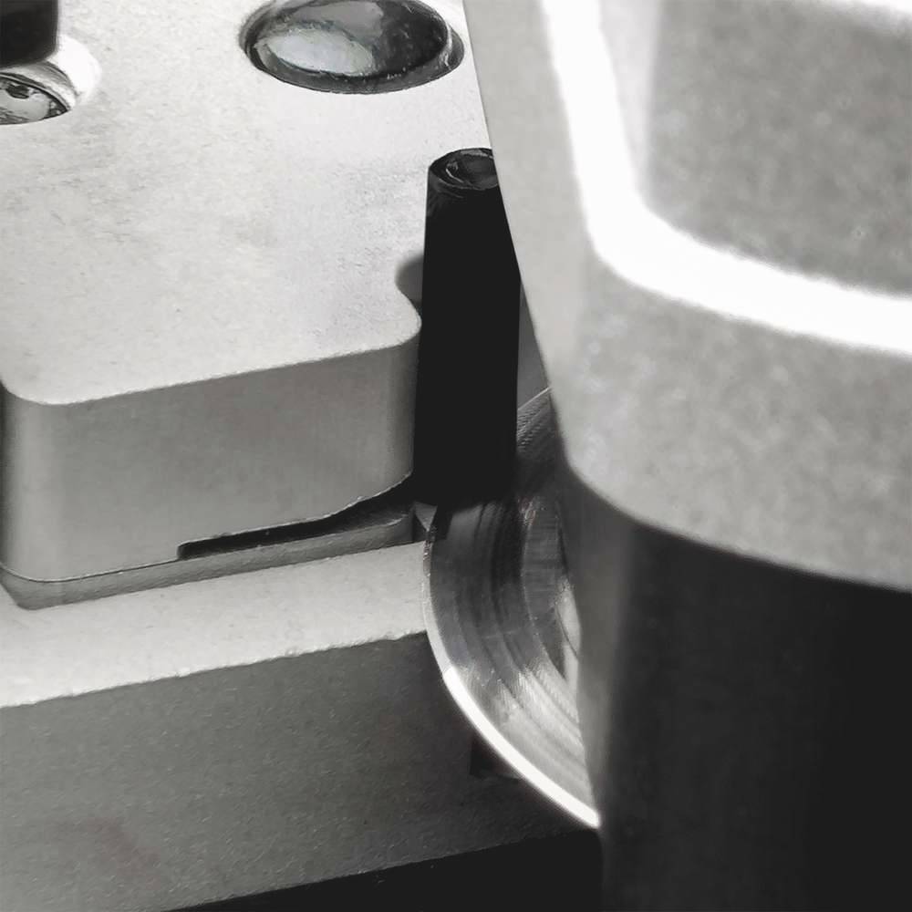 Close-up of a precision machine with metal components and round sensors. Primary function unknown. Industrial setting.