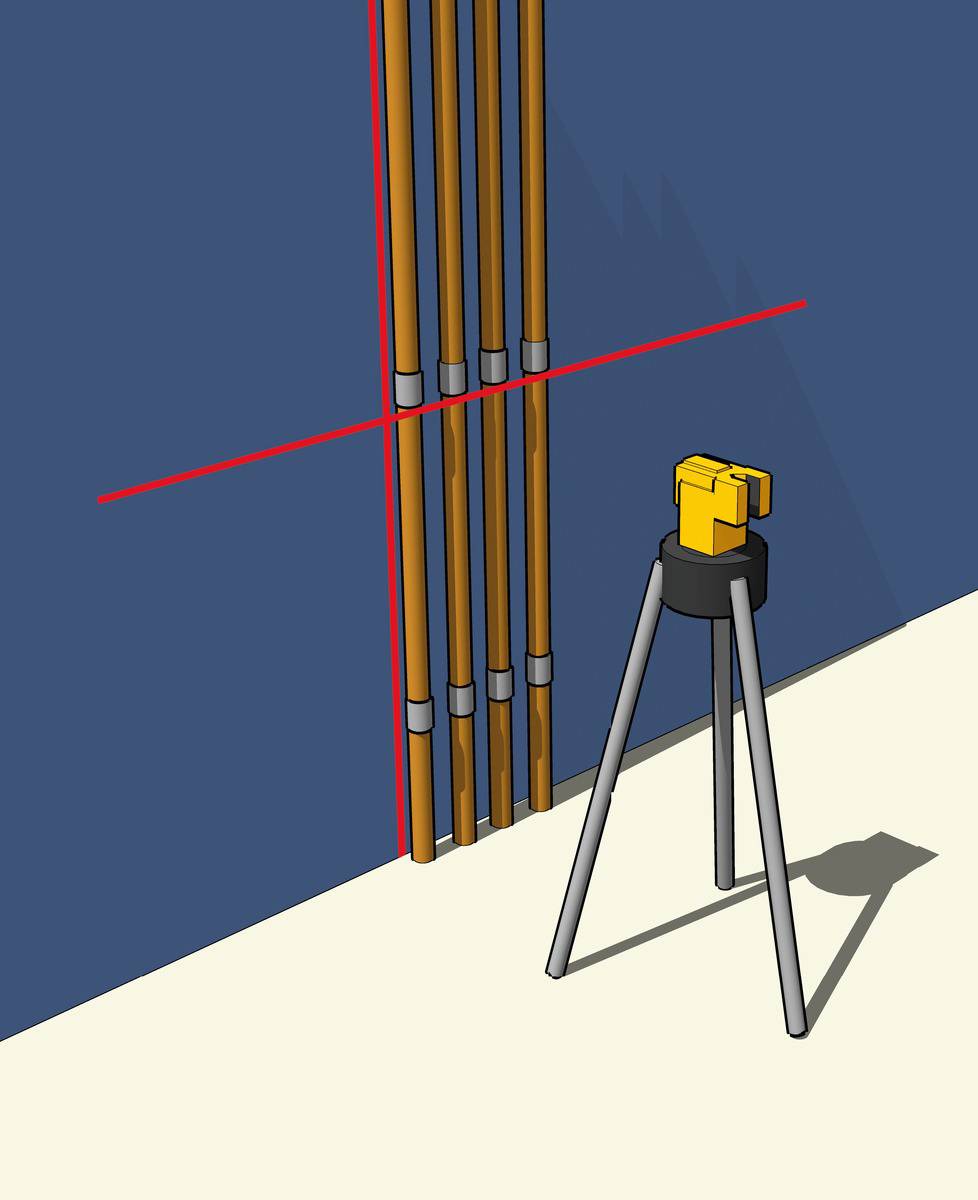 A laser level mounted on a tripod projects red laser lines horizontally and vertically onto a blue wall with four vertical pipes.