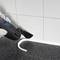 A person is using an electric tool to remove a sealant joint between a worktop and tiles.