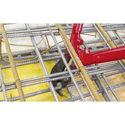A red bolt cutter slices through thick metal struts in a construction site setting.