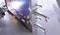 A person is welding metal plates that are secured with clamps to a frame. Sparks are flying on the left side of the image.