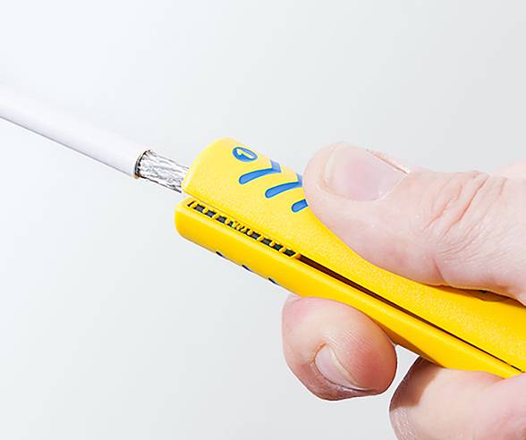 A person holds a yellow lighter, lighting a cylindrical object. The focus is on the lighter and the thumb pressing the ignition.