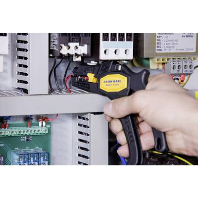 'Hand operating a cable stripper to process cables inside an electrical control cabinet.'