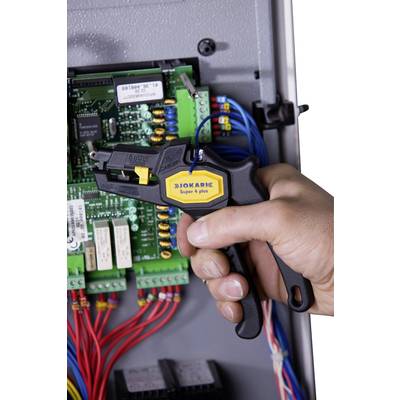 A tradesperson is using a Biokarx Super 4 Plus tool to secure cables in an electrical panel, with visible circuit boards.