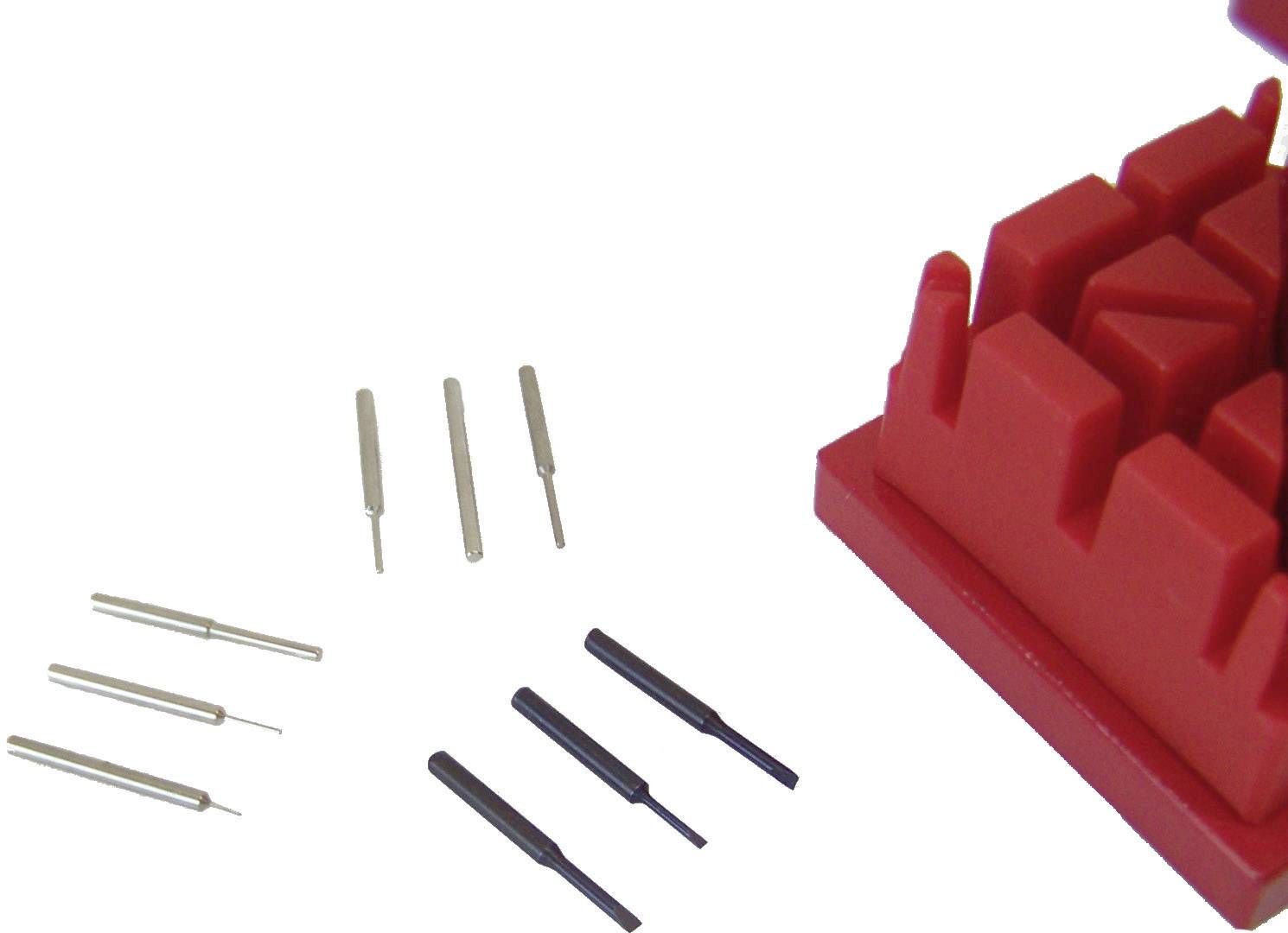 Several metal pins of different sizes next to a red plastic holder.