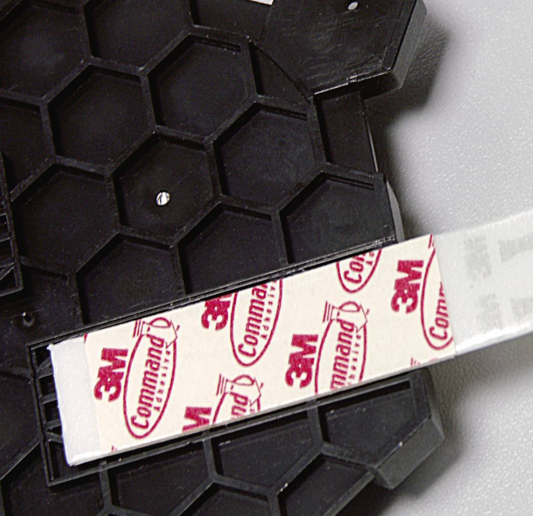 3M Command adhesive strips on a black hexagonal surface. Ideal for hanging without causing damage.