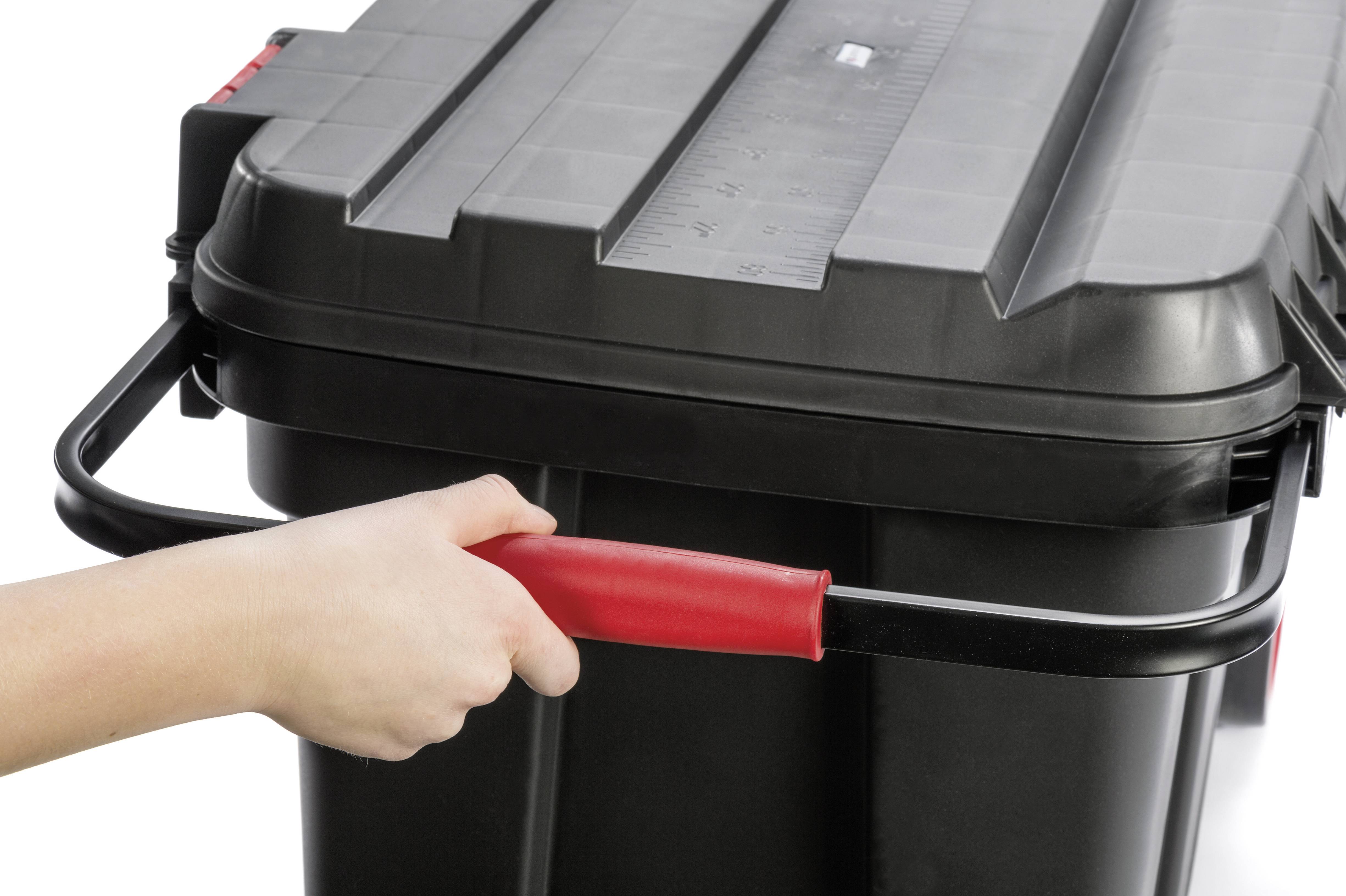 'A hand is holding the red handle of a large black container with a lid.'