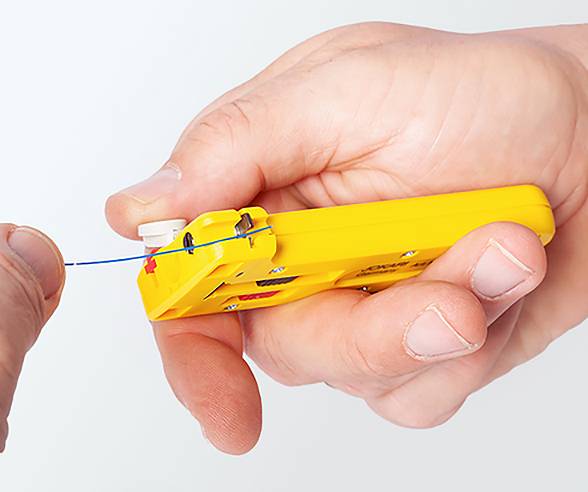 'A person's hands using a yellow wire stripping tool to strip the insulation from a blue wire.'