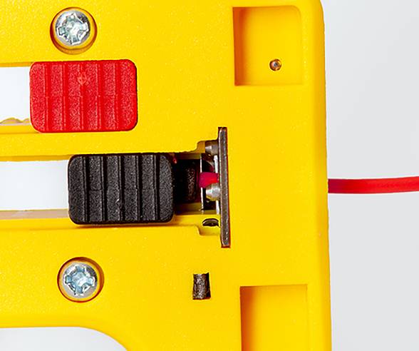 Close-up of a yellow plastic device with screws and a red cable, featuring a black and red switch mechanism in the center.