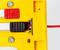 Close-up of a yellow plastic device with screws and a red cable, featuring a black and red switch mechanism in the center.