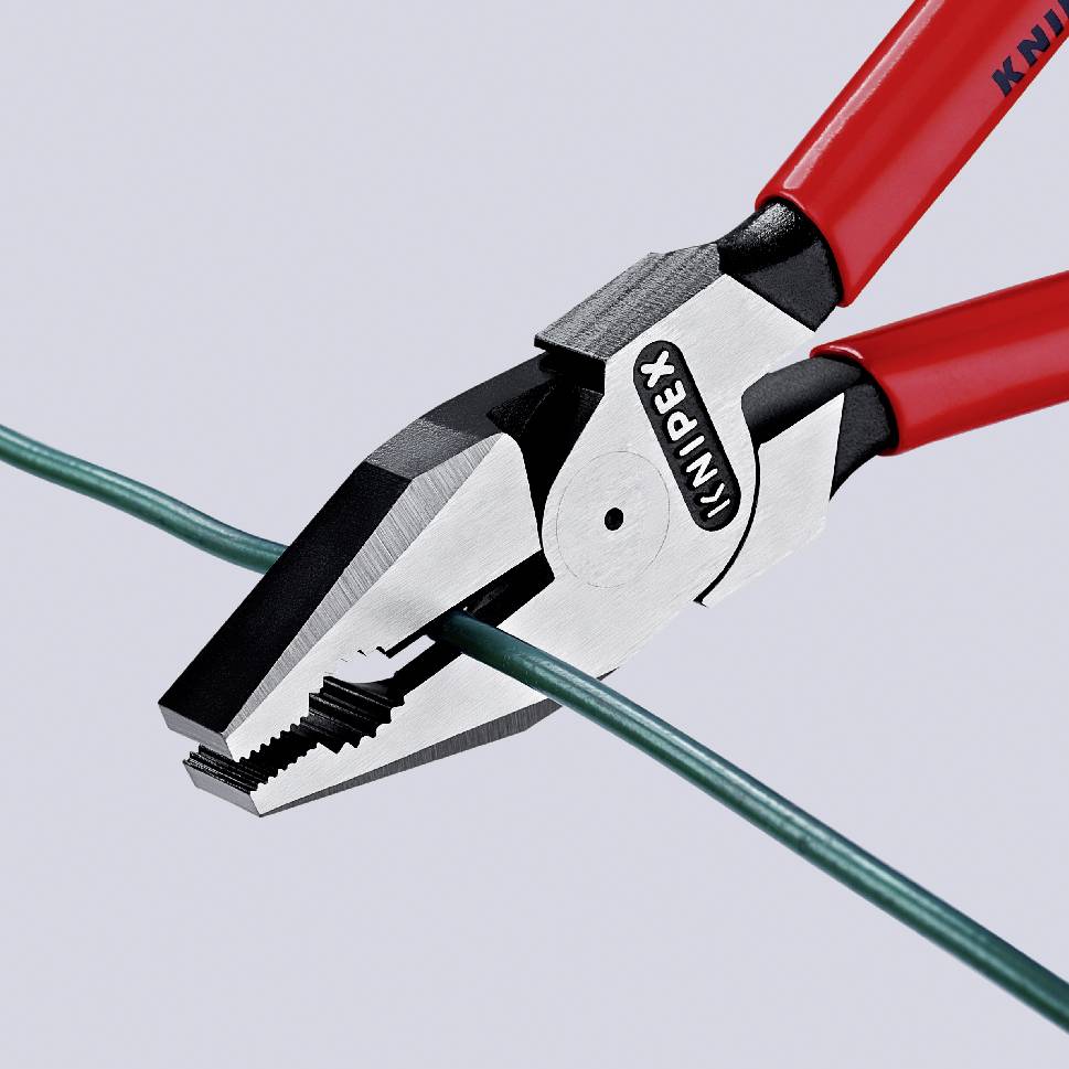 A pair of pliers with red handles is cutting a green wire.