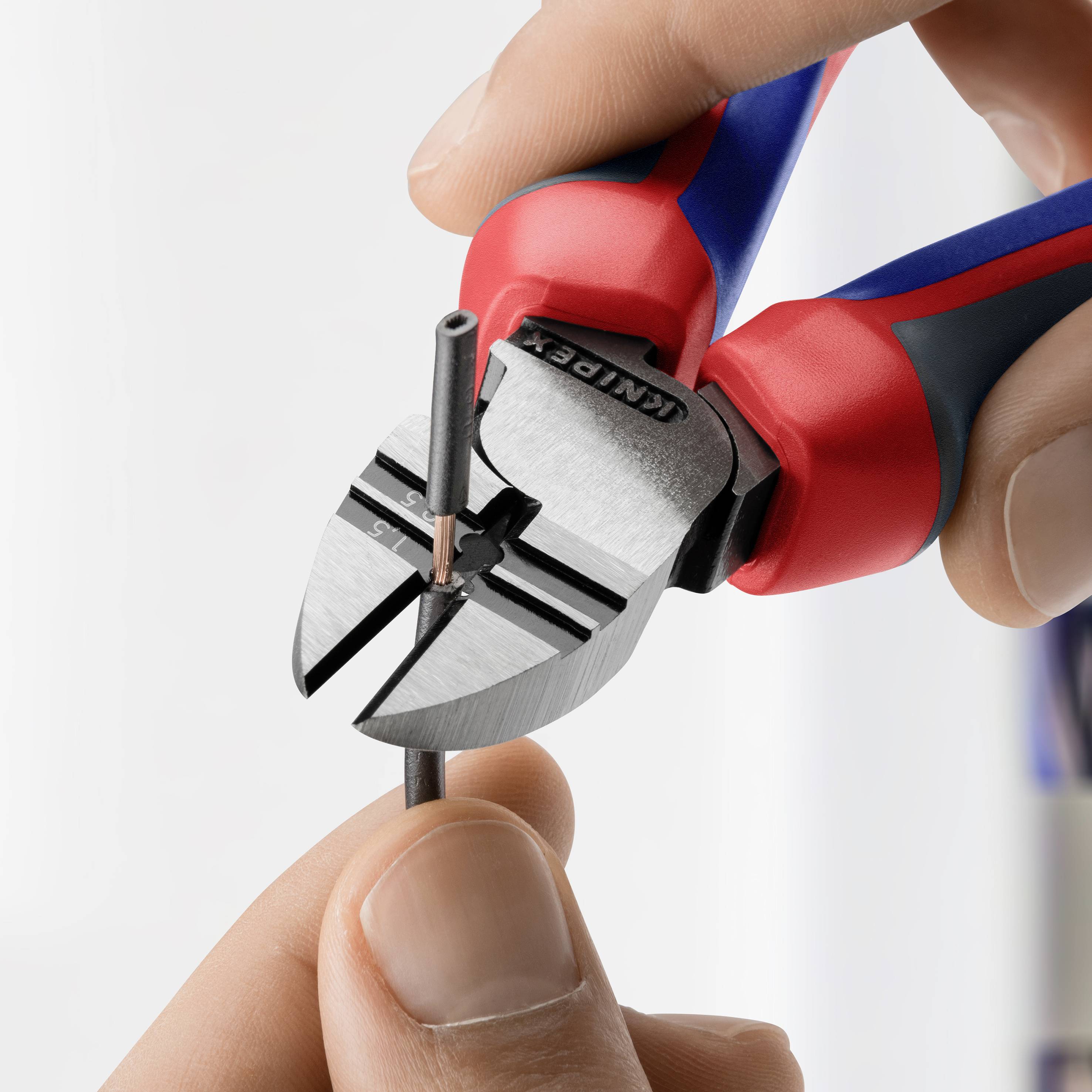 A hand is holding side cutters that are cutting through a thin wire. The pliers are red and blue and have sharp blades.