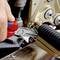 A mechanic holds a red pliers to tighten a screw on a golden mechanical device. Focus on precise work.
