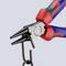 Pliers with blue and red handles are holding a hook. A tool for precise gripping and manipulation of small objects.