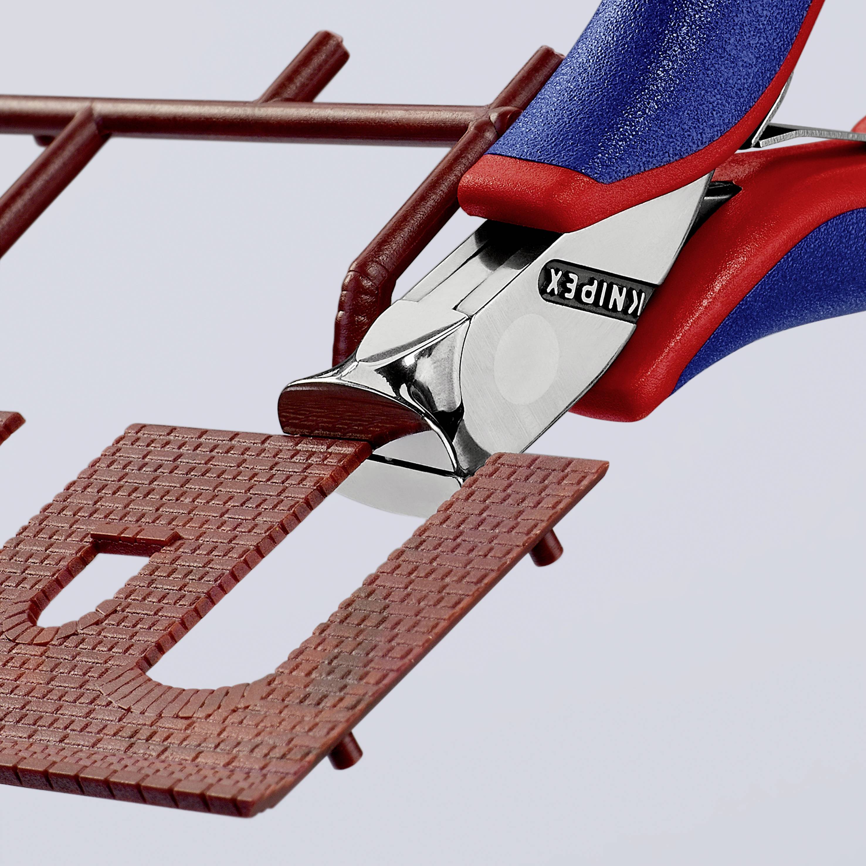 A blue and red pair of pliers precisely cuts a piece of brown wire mesh.