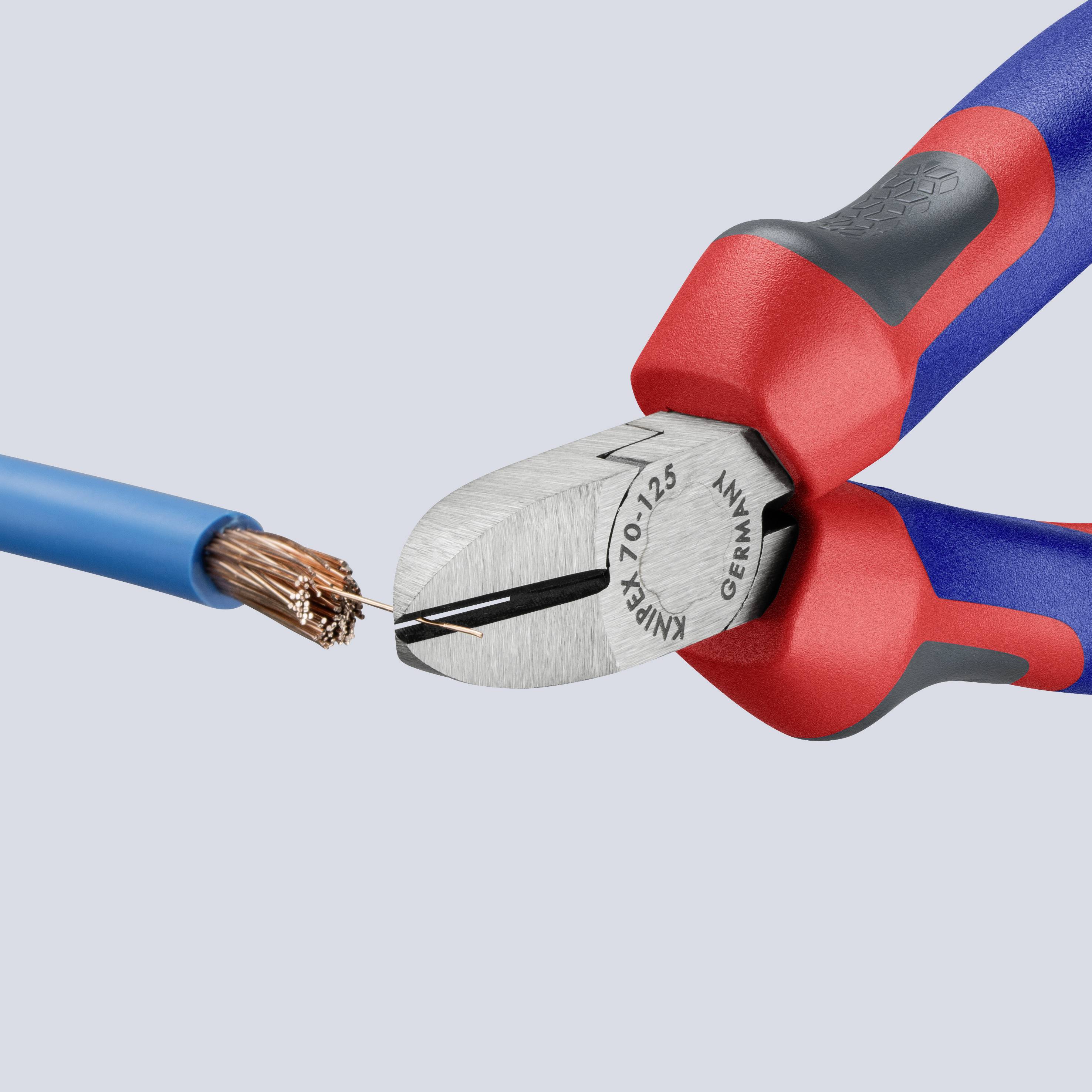 A red and blue pliers cuts a blue cable with copper wires.