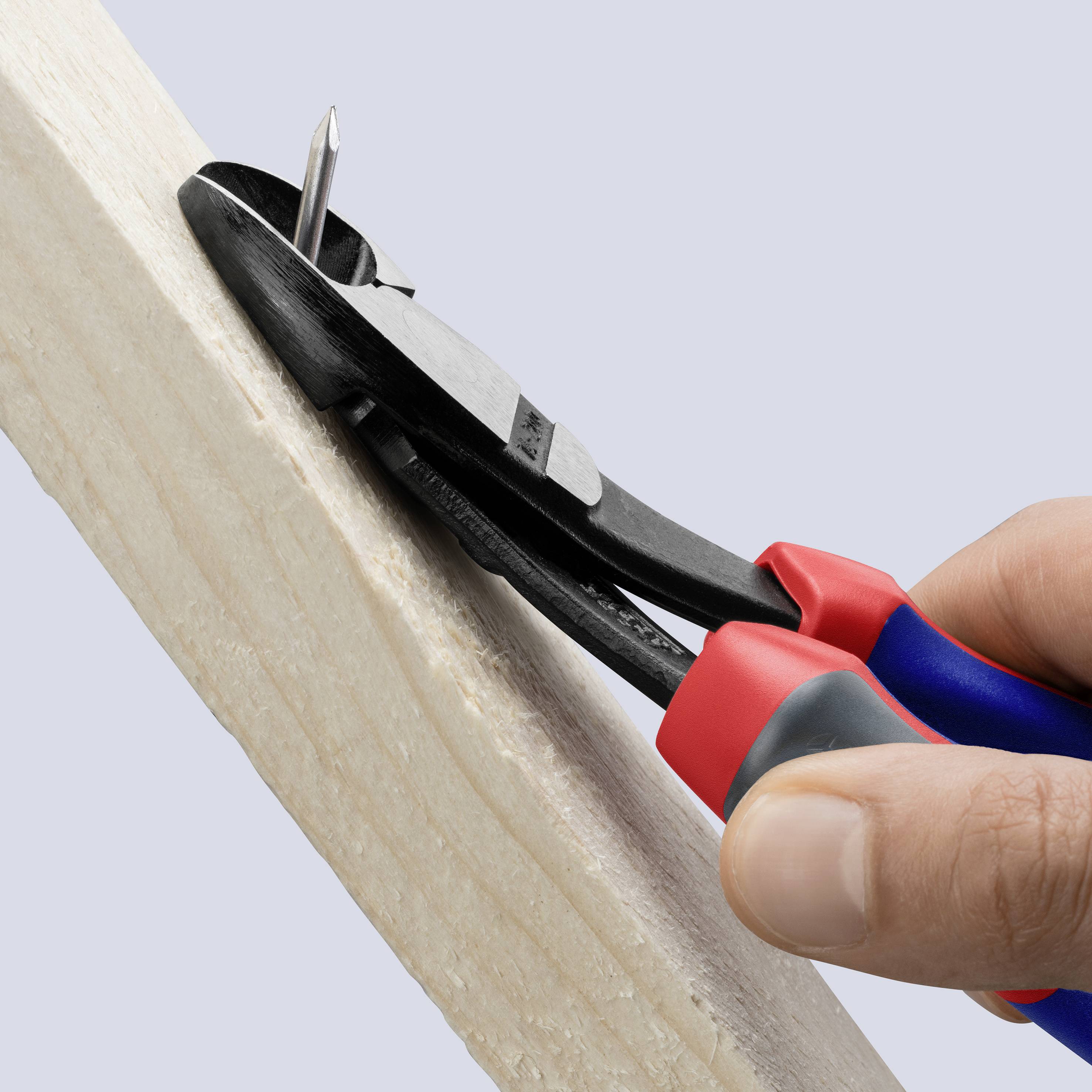 A hand is using a combination pliers to remove a nail from a wooden board.