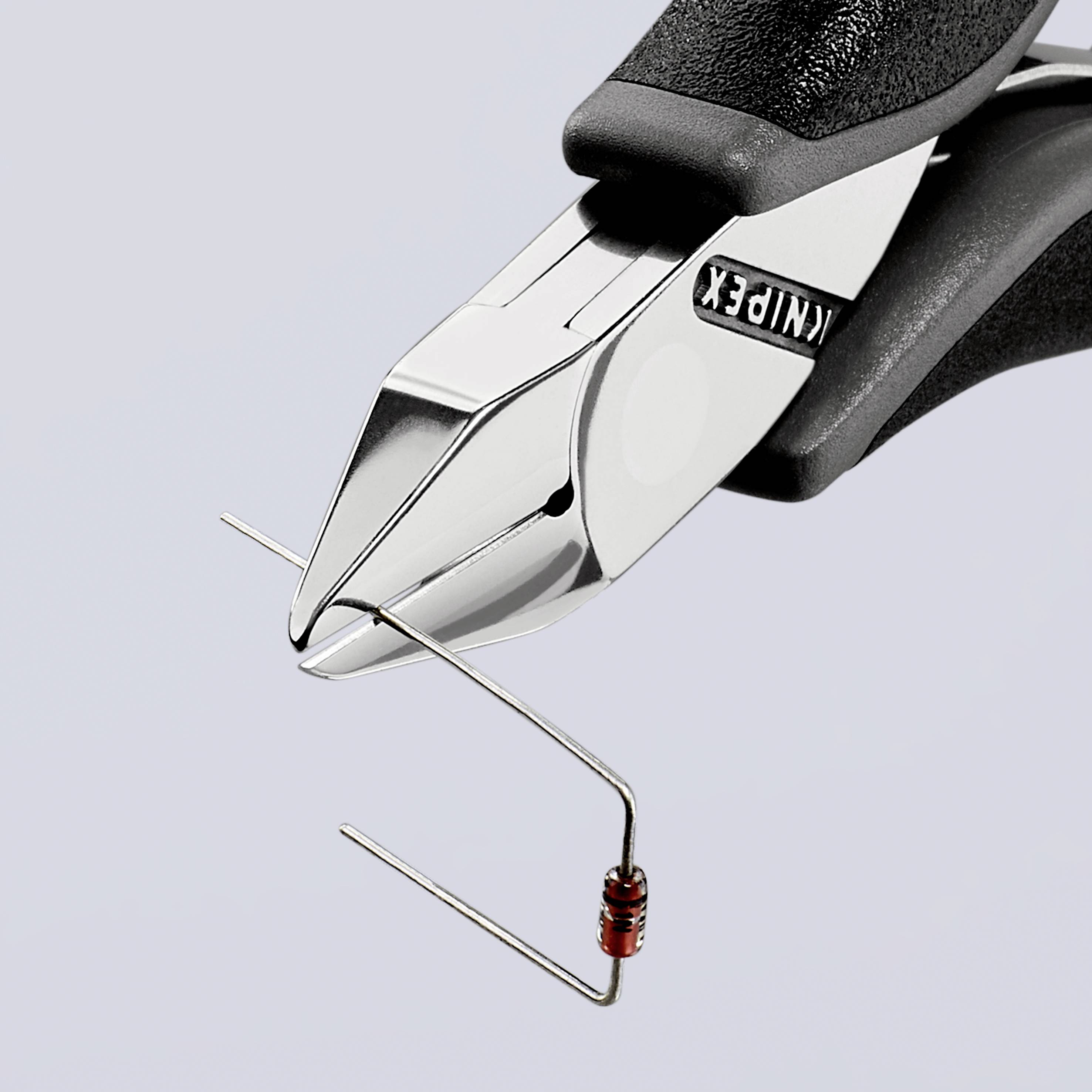 Close-up of pliers cutting a curved wire with a small, red component, likely a resistor.