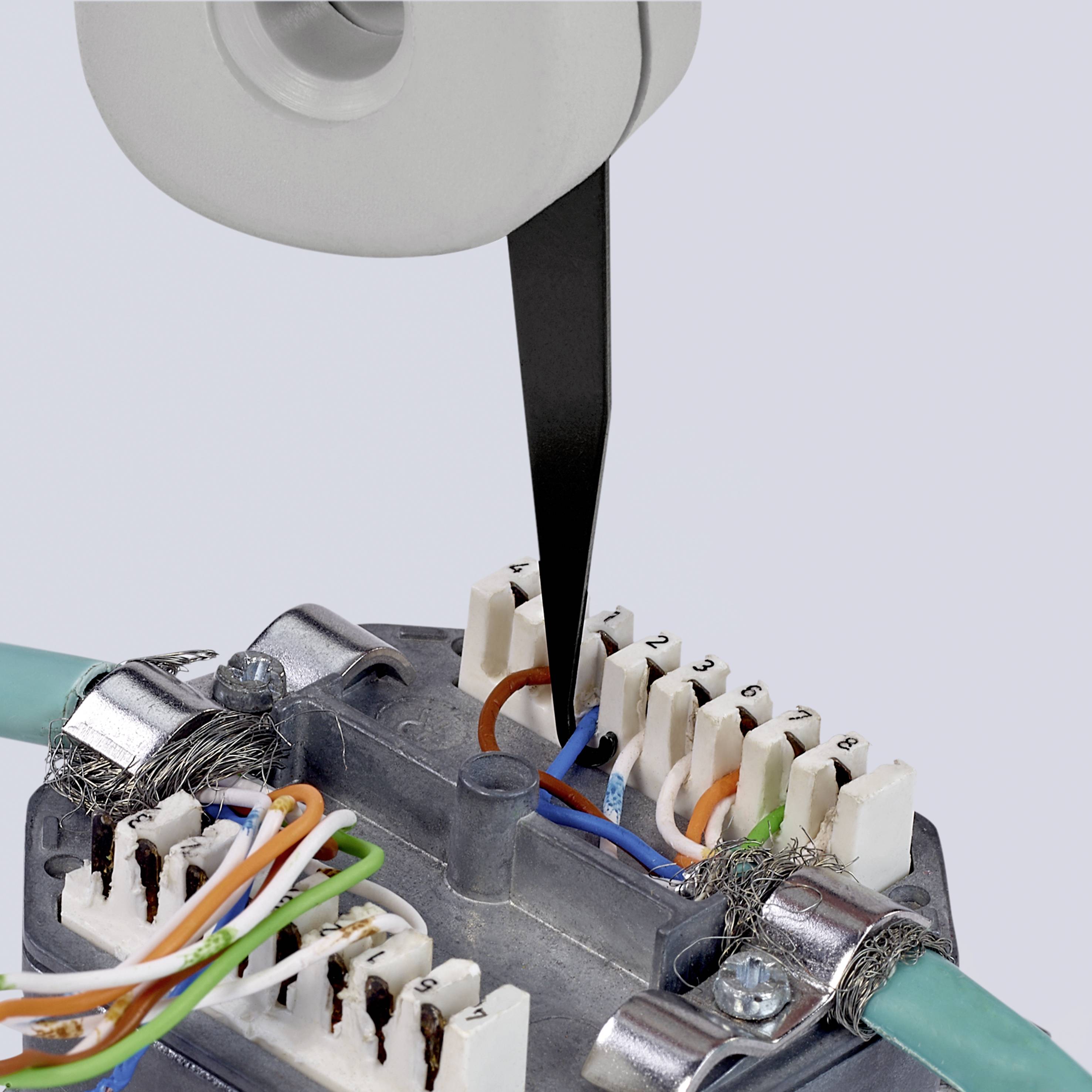 'Close-up of a network distribution box with exposed cabling and tools separating wire cores. Installation in focus.'