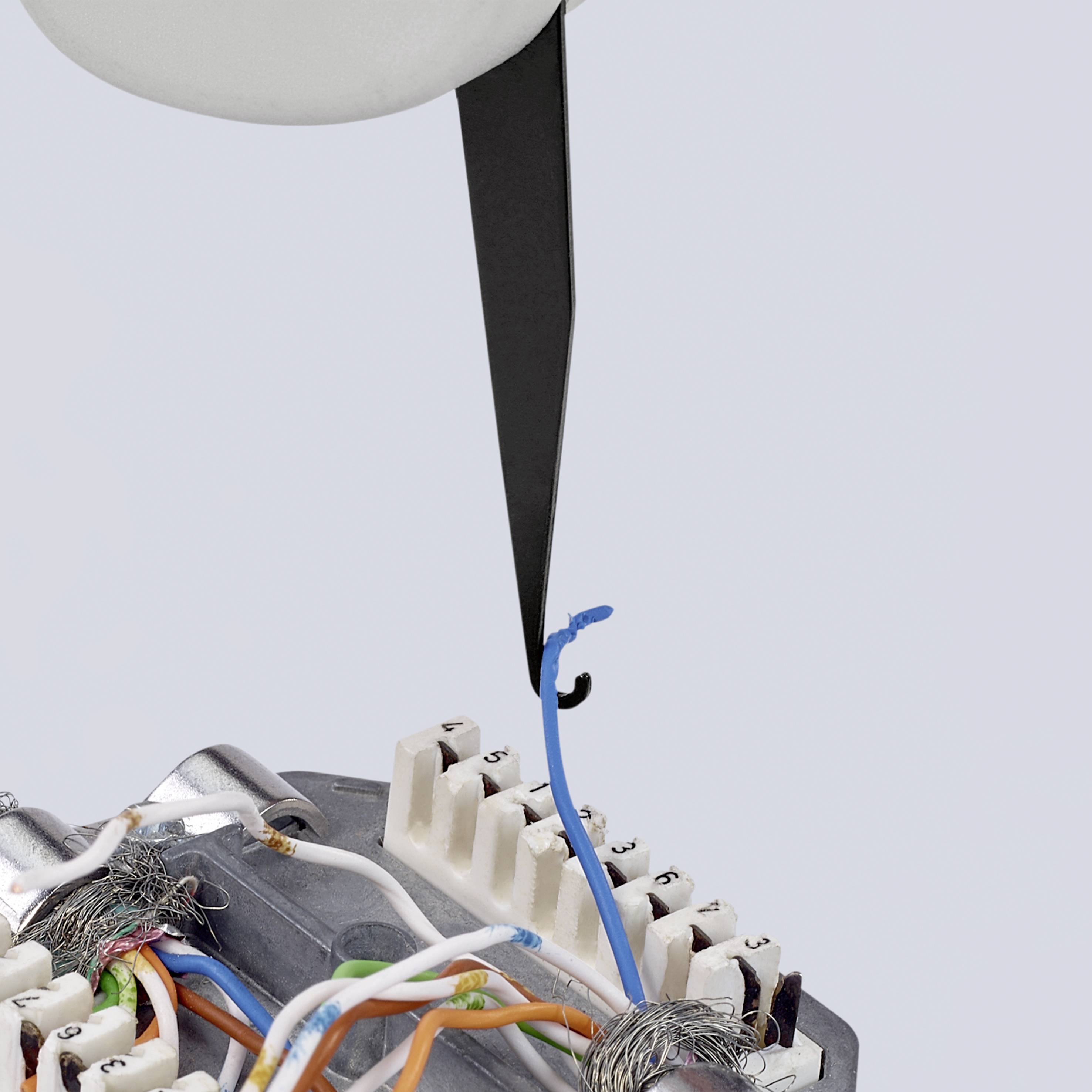 Close-up of a circuit board with coloured cables held by a metal clamp. A sharp black pointer protrudes into the image from the top.