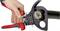 A hand operates a red cable cutter, precisely cutting through a thick cable with visible copper strands.