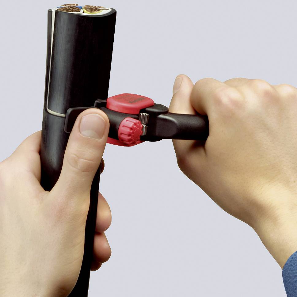A person is using a pipe cutter to cut a black pipe into two parts. Hands are holding the pipe firmly.