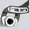 A spanner grips a pipe fitting. The spanner has adjustable jaws suitable for different sizes.
